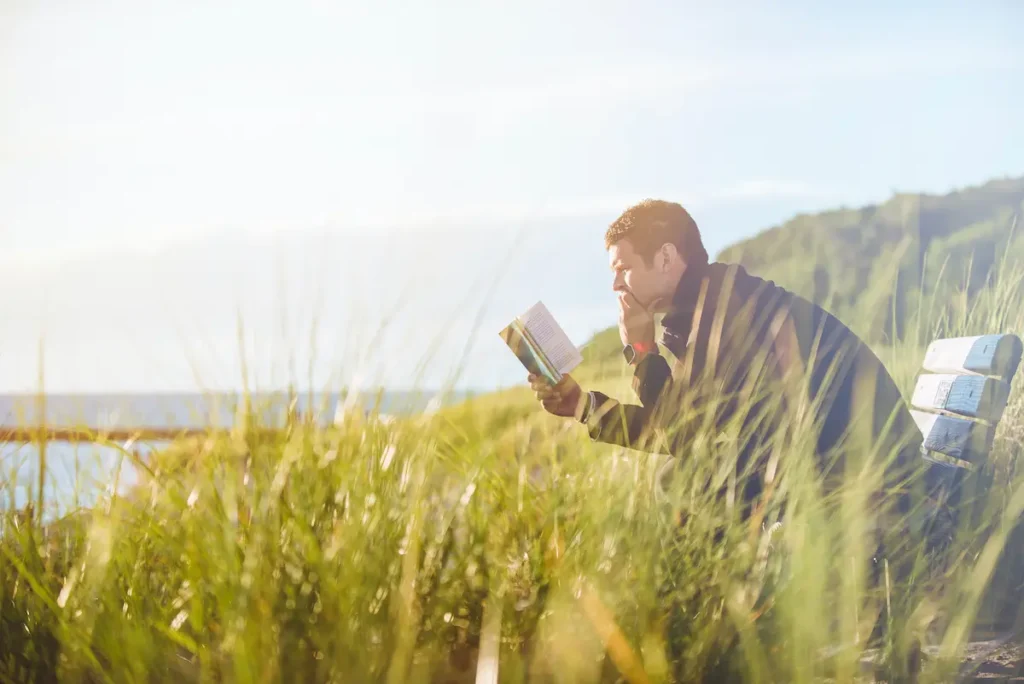 man reading outside in a meadow